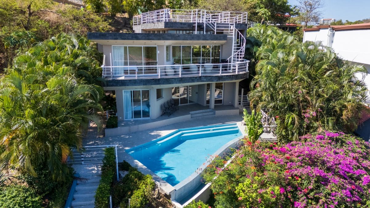 Front view of Casa Nalifos with infinity-edge saltwater pool and tropical landscaping in Playa Flamingo, Costa Rica.