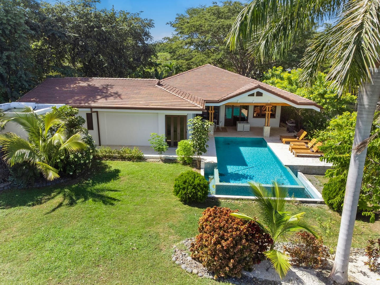 Back view of Casa Artistica, Reserva Conchal, showcasing the private pool and covered terrace, with lush greenery and tropical surroundings.