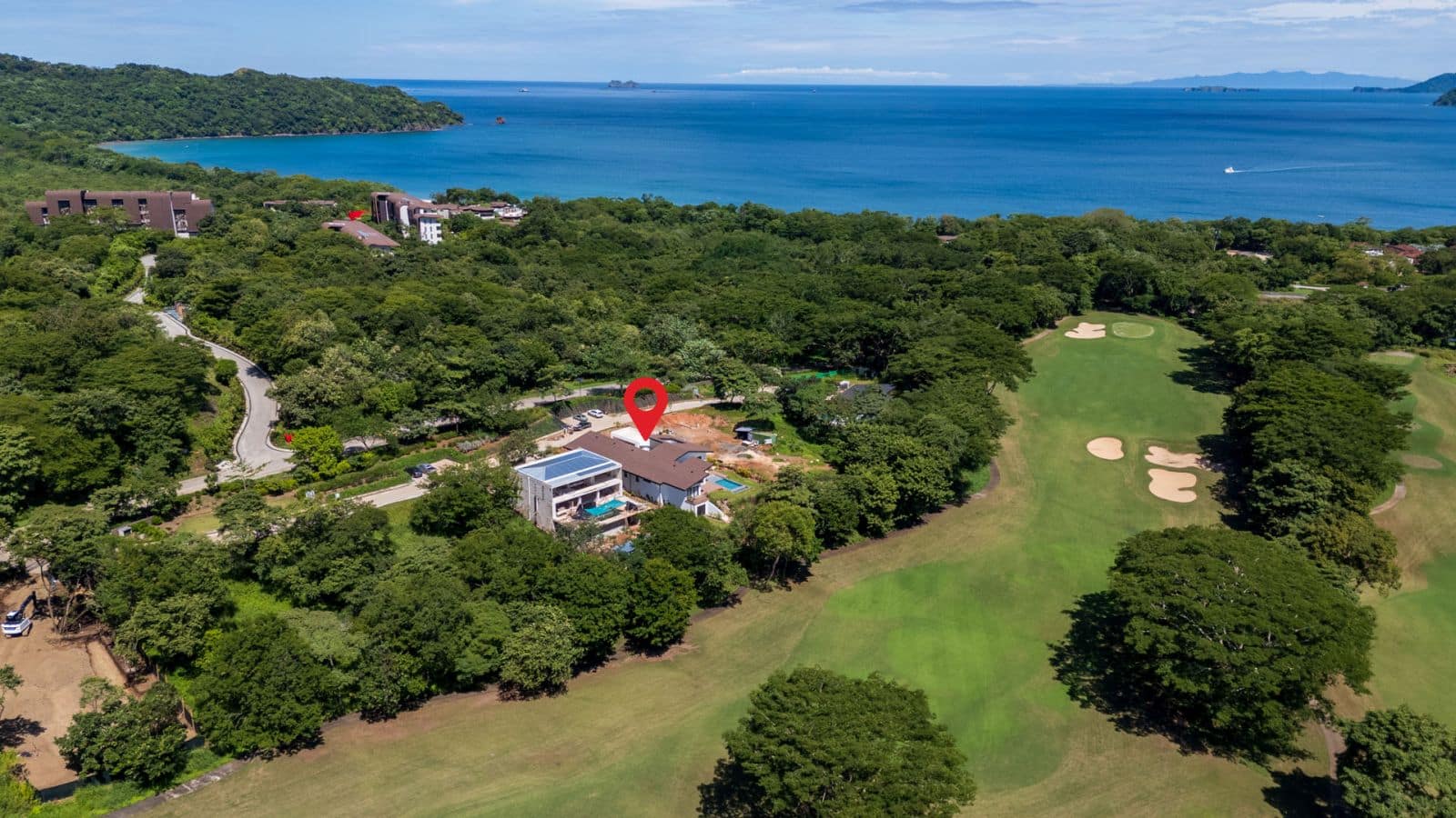 Aerial view of Casa Aguasalada, showcasing the modern design, infinity pool, and lush tropical surroundings with views of the golf course and nearby beach.