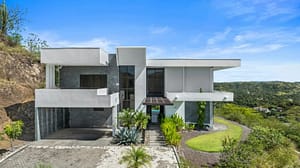 Full front view of Villa Oceana, showcasing modern tropical architecture, large windows, and lush landscaping.