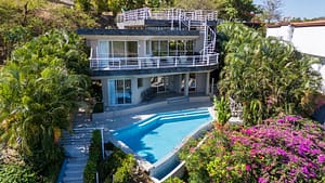 Front view of Casa Nalifos with infinity-edge saltwater pool and tropical landscaping in Playa Flamingo, Costa Rica.