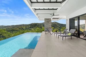 Infinity-edge pool at Villa Oceana with panoramic ocean views, a spacious lounge area, and tropical landscaping.