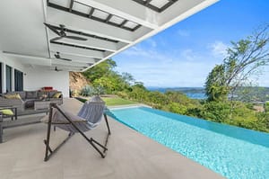 Infinity-edge pool at Villa Oceana with panoramic ocean views, a spacious lounge area, and tropical landscaping.
