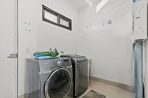 Modern laundry room in Villa Oceana with custom cabinetry, a washer and dryer, and ample storage space.