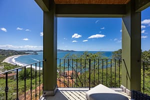 Luxurious ocean-view balcony with glass railings, outdoor seating, and breathtaking panoramic views of Flamingo Marina and the Pacific Ocean.