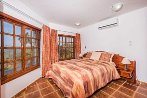 Spacious bedroom with teak wood accents and ocean view at Casa Margarita, Playa Flamingo