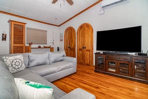 Spacious and stylish living room with modern furnishings, floor-to-ceiling windows, and stunning views of Arenal Volcano and the tropical rainforest.