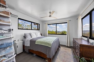 Cozy and bright bedroom in the guest house with large windows, modern furnishings, and a tranquil ambiance.