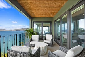 Luxurious ocean-view balcony with glass railings, outdoor seating, and breathtaking panoramic views of Flamingo Marina and the Pacific Ocean.