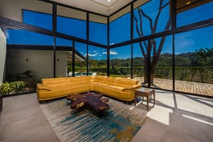 Bright modern living room with high ceilings, open layout, and golf course views at Llama del Bosque 27 in Reserva Conchal