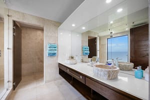 Luxurious ensuite bathroom with custom stone sinks and oversized rain shower overlooking the ocean at Casa Seahorse in Mar Vista, Playa Flamingo.