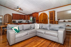 Spacious and stylish living room with modern furnishings, floor-to-ceiling windows, and stunning views of Arenal Volcano and the tropical rainforest.