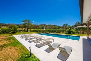 Private pool deck with sun loungers, jacuzzi, and tropical garden views at Llama del Bosque 27, Reserva Conchal