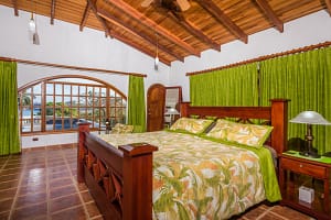 Spacious bedroom with teak wood accents and ocean view at Casa Margarita, Playa Flamingo