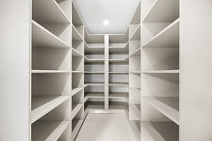 Spacious walk-in closet in Casa Aguasalada, featuring custom teak shelving, ample storage, and elegant lighting.