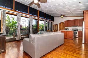 Spacious and stylish living room with modern furnishings, floor-to-ceiling windows, and stunning views of Arenal Volcano and the tropical rainforest.