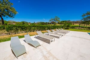 Private pool deck with sun loungers, jacuzzi, and tropical garden views at Llama del Bosque 27, Reserva Conchal