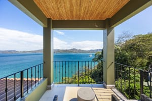 Luxurious ocean-view balcony with glass railings, outdoor seating, and breathtaking panoramic views of Flamingo Marina and the Pacific Ocean.