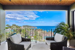 Luxurious ocean-view balcony with glass railings, outdoor seating, and breathtaking panoramic views of Flamingo Marina and the Pacific Ocean.