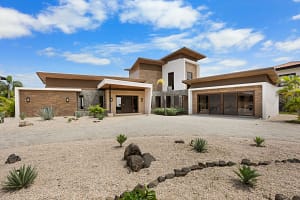 Front view of Casa Seahorse showcasing its modern architecture, elegant stone and wood accents, and lush tropical landscaping in Mar Vista, Playa Flamingo.