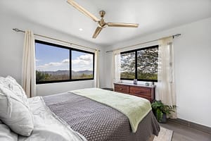 Cozy and bright bedroom in the guest house with large windows, modern furnishings, and a tranquil ambiance.