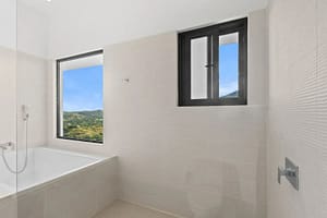 Master bathroom at Villa Oceana featuring a walk-in closet, dual vanities, and a soaking tub with ocean views.
