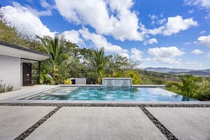Luxurious infinity-edge pool with a cascading waterfall, surrounded by lush tropical gardens and stunning mountain views.