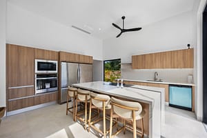 Modern open-concept kitchen in Casa Aguasalada, featuring sleek countertops, high-end appliances, and elegant teak cabinetry with a spacious island.