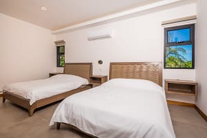 Spacious guest bedroom with two beds, modern decor, and garden views at Llama del Bosque 27, Reserva Conchal