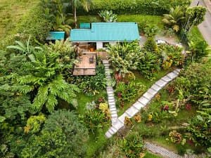 Aerial view of a luxury mountain retreat near Arenal Volcano, featuring two elegant homes, lush tropical gardens, and breathtaking rainforest surroundings.