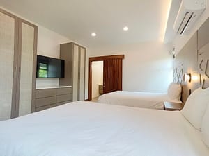 Spacious guest bedroom with two beds, modern decor, and garden views at Llama del Bosque 27, Reserva Conchal
