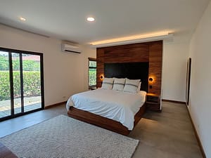 Luxurious master bedroom with king bed, high ceilings, and pool views at Llama del Bosque 27 in Reserva Conchal